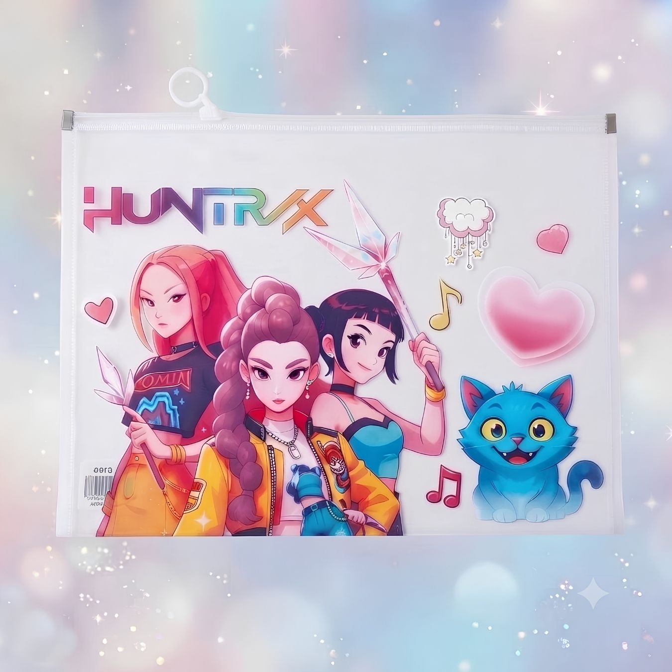 A white hanging file folder or document holder featuring colorful anime-style artwork with the text 'HUNTRX' at the top, illustrated characters, hearts, music notes, and a blue cat illustration, shown against a soft pastel sparkly background.