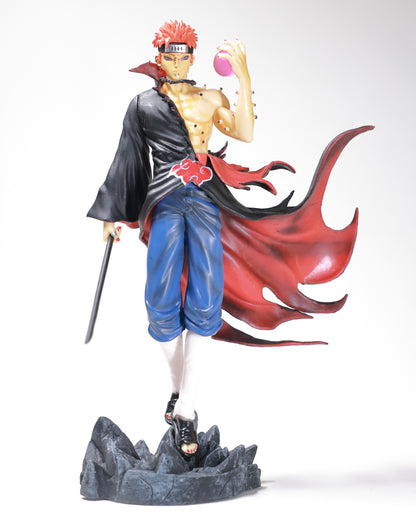 Anime character Naruto pain figurine with a red hair and sharingan eye, dressed in a black and blue outfit, holding a sword, and standing on a rock base.